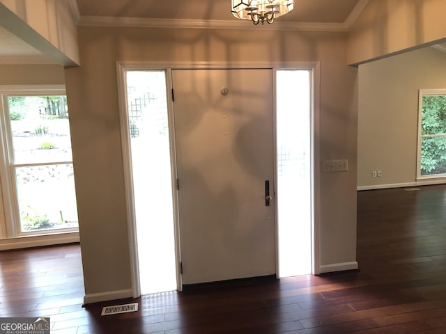 entrance foyer featuring crown molding, dark wood-type flooring, and an inviting chandelier