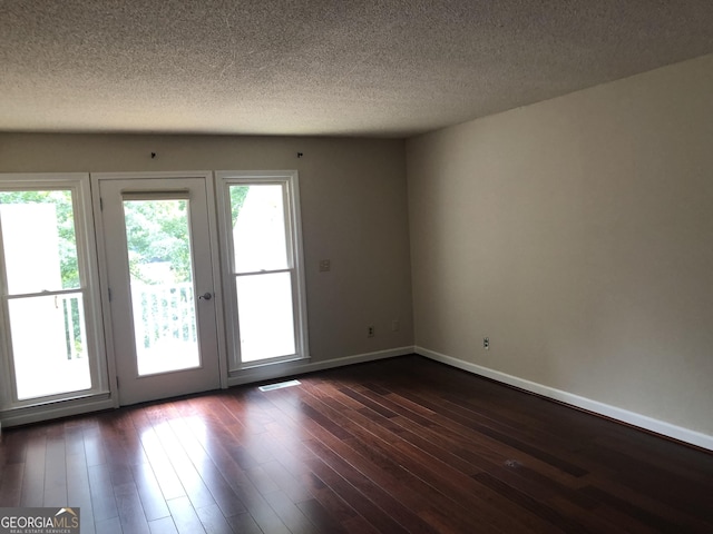 unfurnished room featuring a textured ceiling and dark hardwood / wood-style flooring