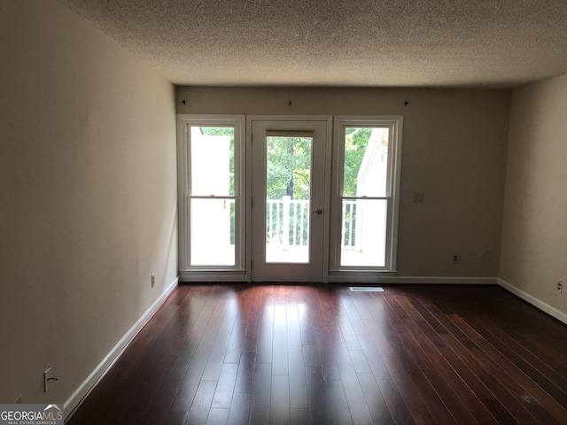 doorway with a textured ceiling and dark hardwood / wood-style floors