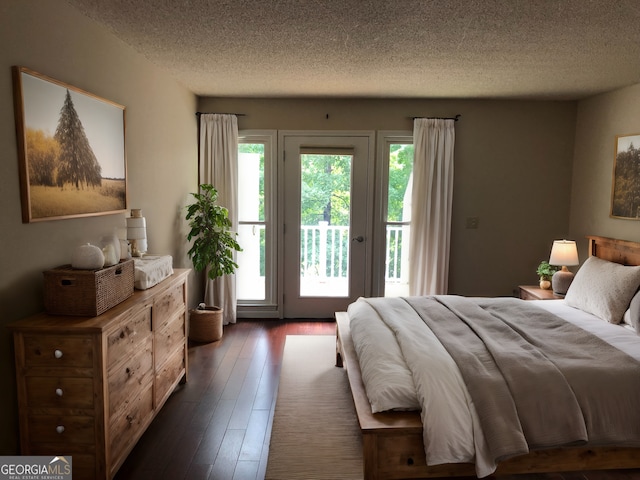 bedroom with access to exterior, dark hardwood / wood-style floors, and a textured ceiling