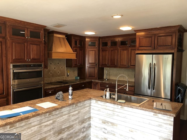 kitchen with appliances with stainless steel finishes, sink, backsplash, premium range hood, and light stone counters