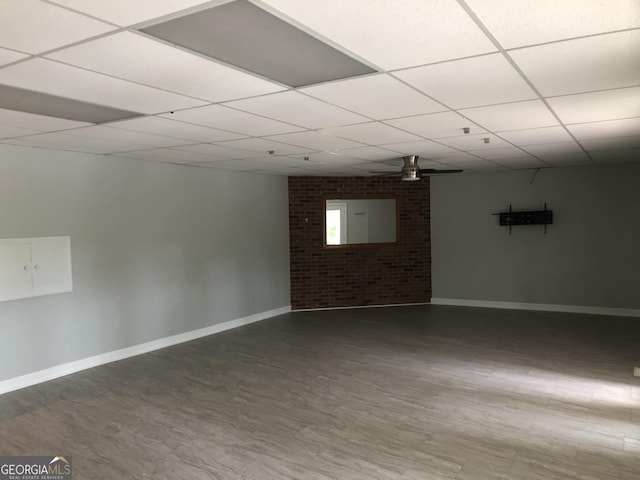 basement featuring brick wall and a drop ceiling