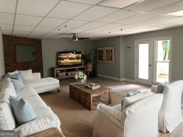 living room with ceiling fan and a drop ceiling