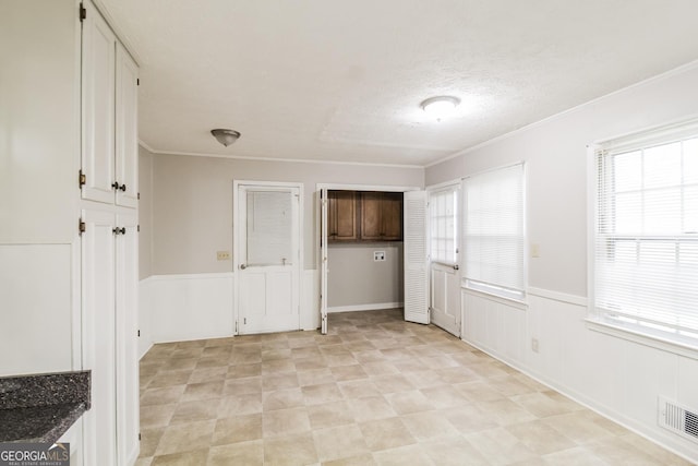 laundry area with a textured ceiling, cabinets, and ornamental molding