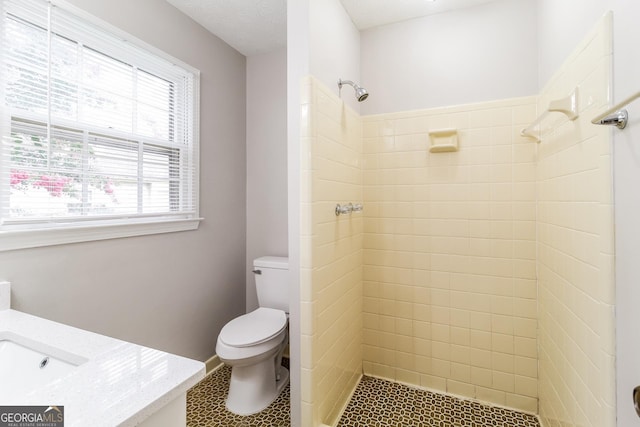 bathroom featuring toilet, vanity, and tiled shower