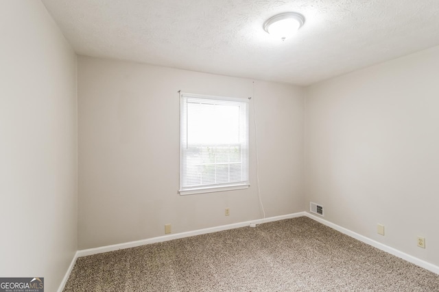 empty room with a textured ceiling and carpet flooring