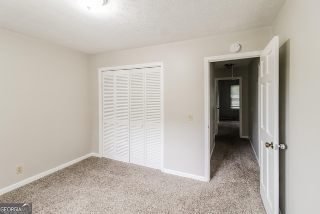 unfurnished bedroom featuring light colored carpet, a closet, and a textured ceiling