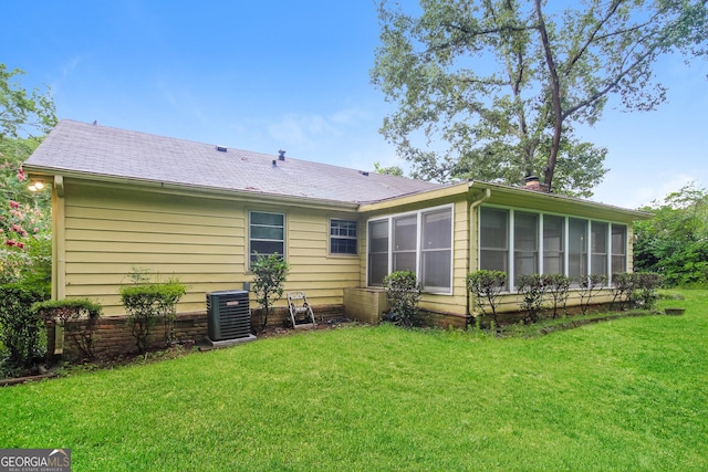 rear view of house featuring central AC, a yard, and a sunroom