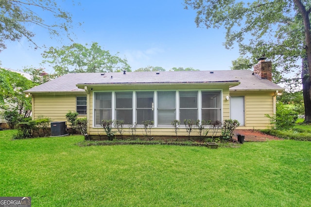 rear view of house with central air condition unit and a yard