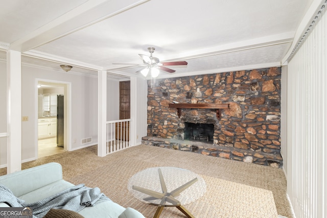 living room with carpet floors, beamed ceiling, a fireplace, ceiling fan, and crown molding