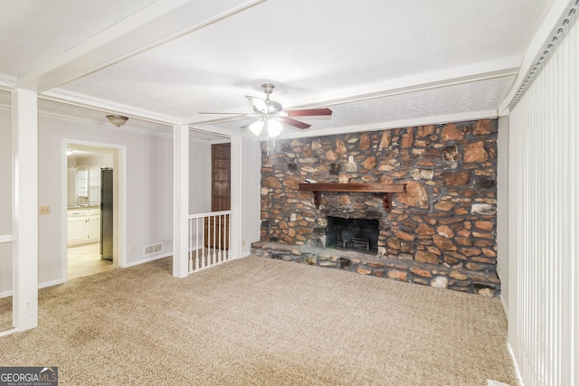 unfurnished living room with ceiling fan, carpet flooring, ornamental molding, and a stone fireplace