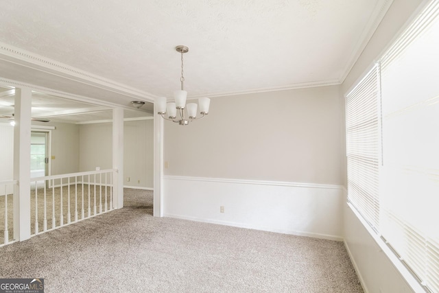 carpeted spare room featuring ornamental molding and a chandelier