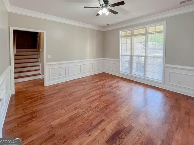 empty room featuring hardwood / wood-style flooring, ornamental molding, and ceiling fan