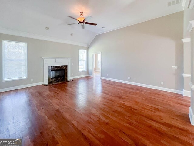 unfurnished living room with hardwood / wood-style floors, lofted ceiling, ornamental molding, ceiling fan, and a high end fireplace