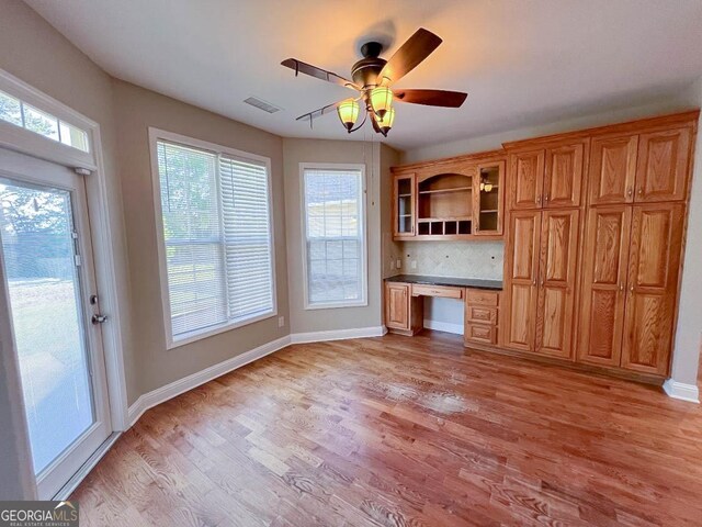 kitchen with light hardwood / wood-style flooring, backsplash, built in desk, and ceiling fan