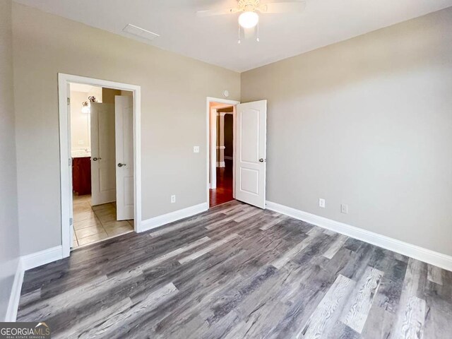 unfurnished bedroom featuring hardwood / wood-style floors, ensuite bath, and ceiling fan