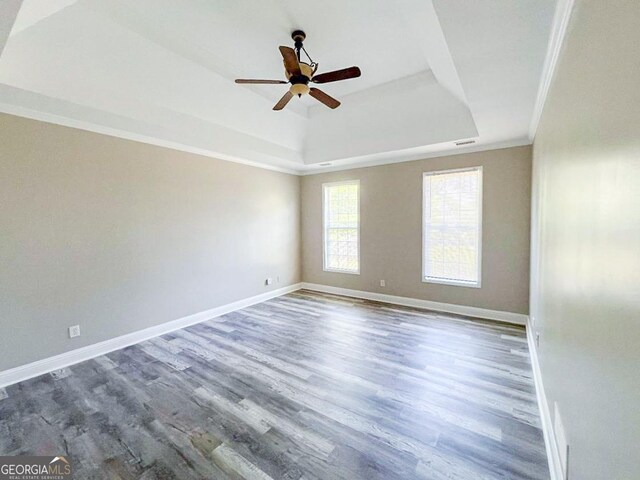 empty room featuring crown molding, ceiling fan, a raised ceiling, and hardwood / wood-style floors