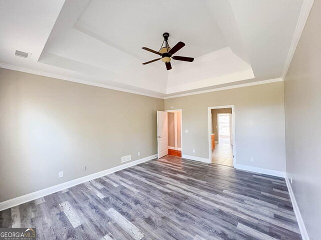 unfurnished bedroom with ornamental molding, hardwood / wood-style floors, ceiling fan, and a tray ceiling