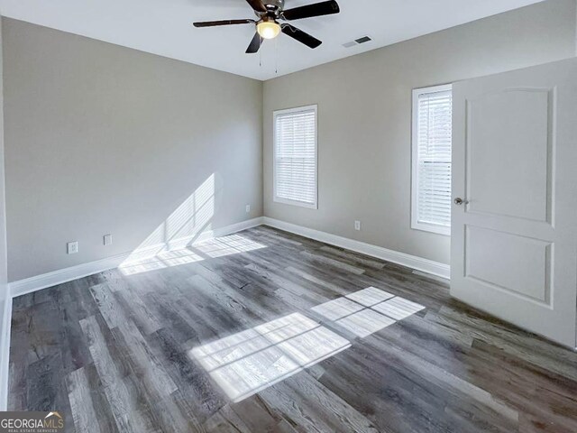 spare room with ceiling fan, dark wood-type flooring, and a healthy amount of sunlight