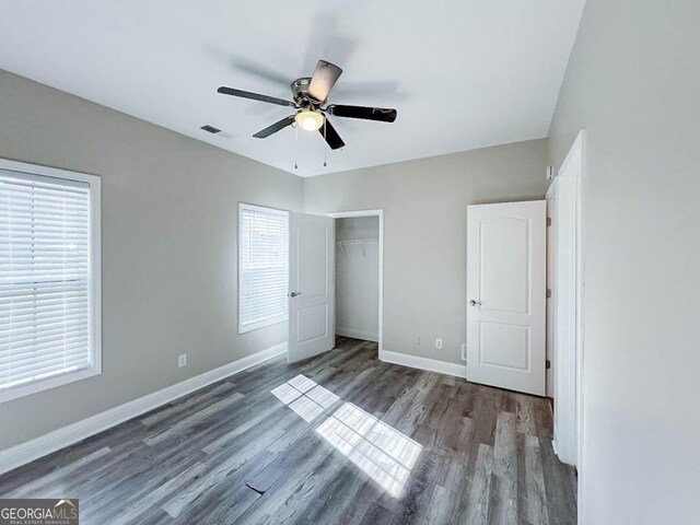 unfurnished bedroom with dark hardwood / wood-style flooring, a closet, and ceiling fan