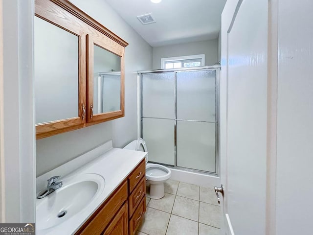 bathroom featuring vanity, a shower with shower door, tile patterned floors, and toilet