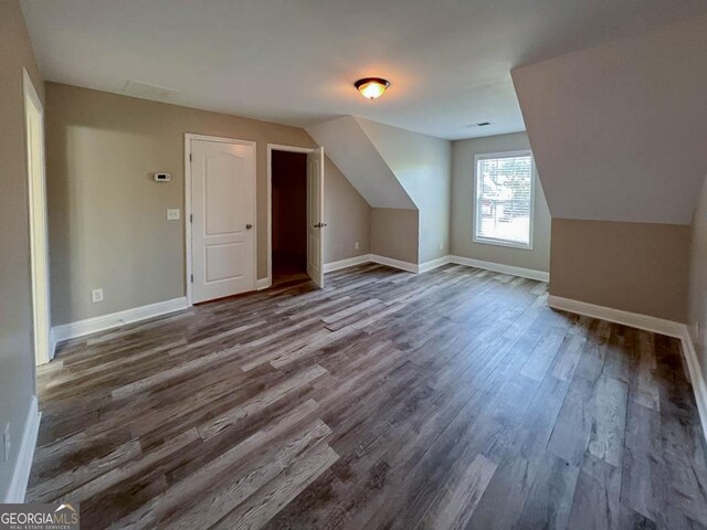 bonus room with dark wood-type flooring and lofted ceiling