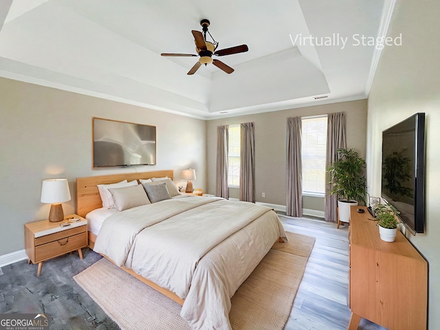 bedroom with hardwood / wood-style flooring, ceiling fan, crown molding, and a raised ceiling