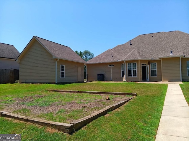 back of property with a yard and central AC