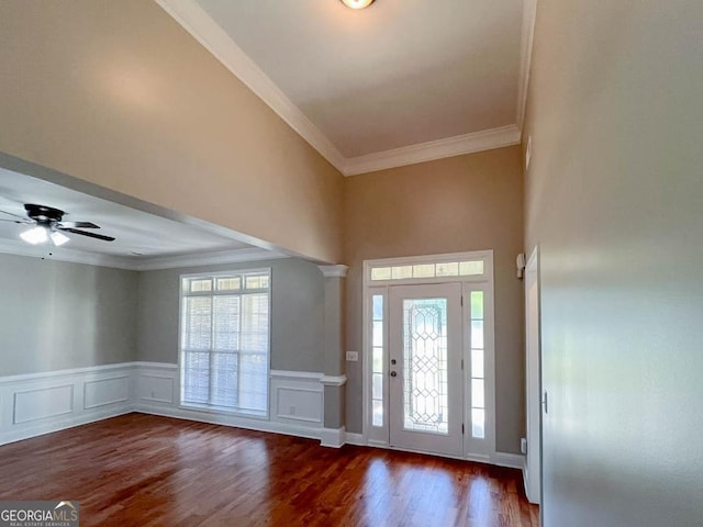 foyer entrance featuring crown molding, ceiling fan, dark hardwood / wood-style flooring, and ornate columns