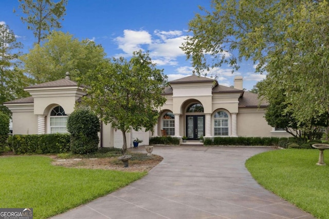 mediterranean / spanish house featuring a garage and a front lawn