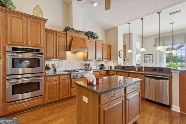 kitchen featuring custom range hood, backsplash, stainless steel appliances, light hardwood / wood-style floors, and high vaulted ceiling