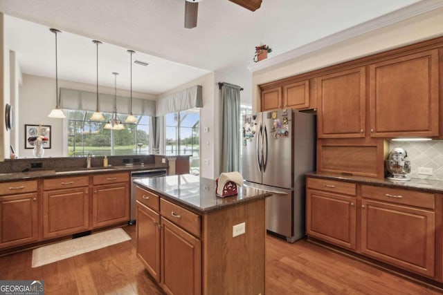 kitchen featuring sink, stainless steel refrigerator, ceiling fan with notable chandelier, a center island, and hardwood / wood-style flooring