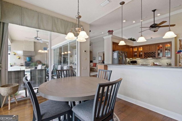 dining area featuring ornamental molding, ceiling fan with notable chandelier, and hardwood / wood-style flooring