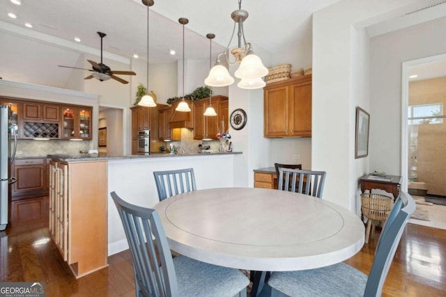 dining area featuring dark hardwood / wood-style flooring, ceiling fan, and a towering ceiling