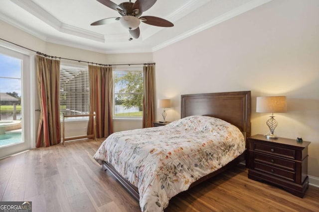 bedroom with a raised ceiling, access to outside, ceiling fan, wood-type flooring, and ornamental molding