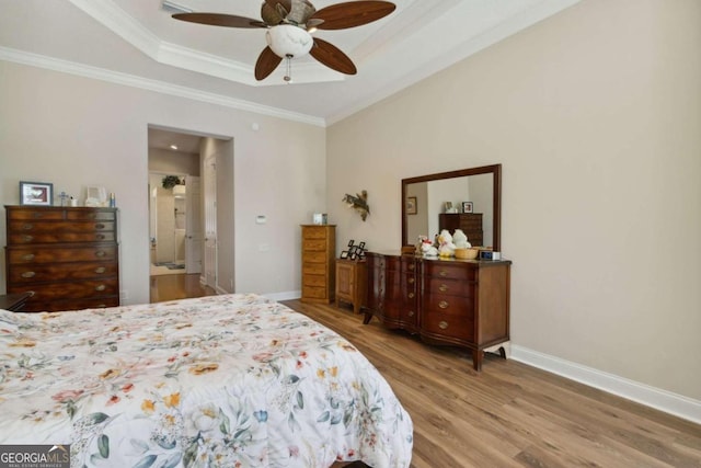 bedroom with ornamental molding, light hardwood / wood-style flooring, ceiling fan, and a raised ceiling