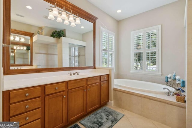 bathroom featuring vanity, tile patterned floors, a healthy amount of sunlight, and tiled bath