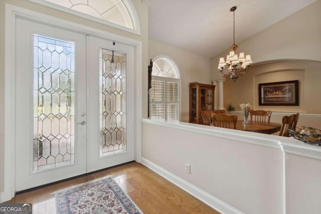 foyer entrance with an inviting chandelier, lofted ceiling, light wood-type flooring, and a healthy amount of sunlight