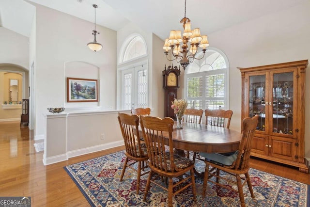 dining area with high vaulted ceiling, a chandelier, and hardwood / wood-style flooring