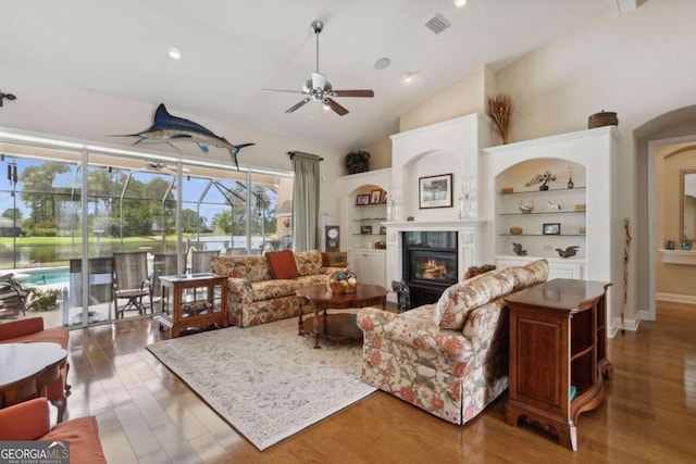 living room with wood-type flooring, built in features, high vaulted ceiling, and ceiling fan