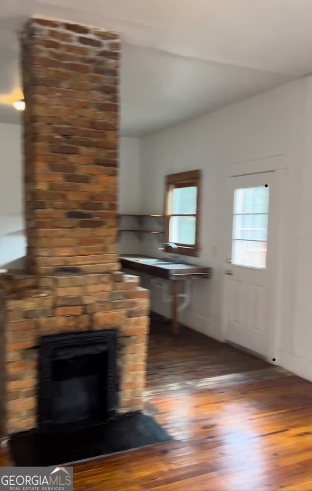 unfurnished living room with wood-type flooring and brick wall