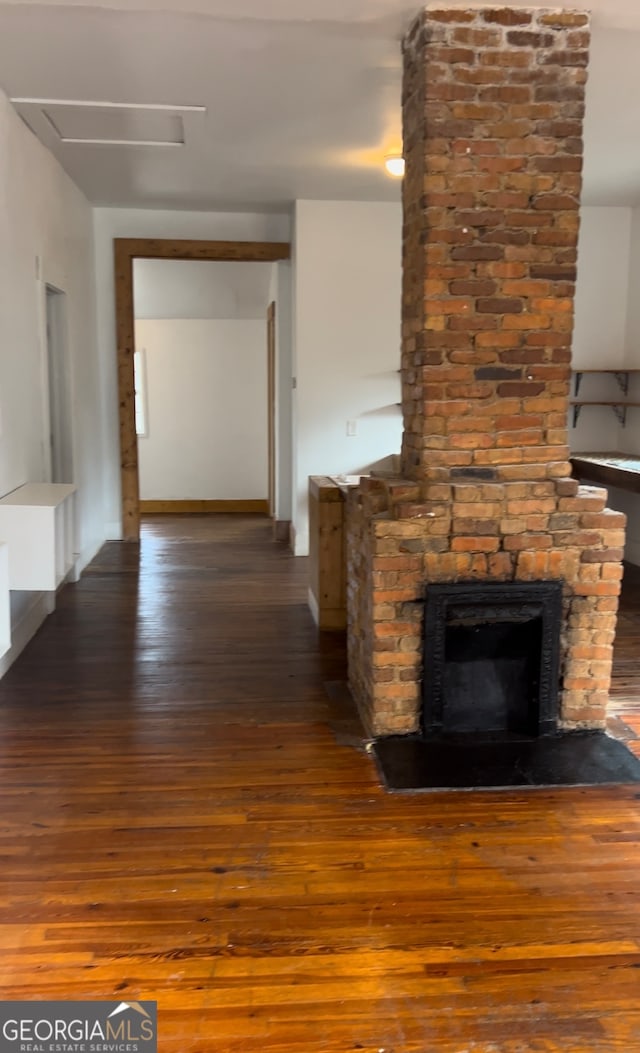 unfurnished living room with a large fireplace, brick wall, and hardwood / wood-style floors