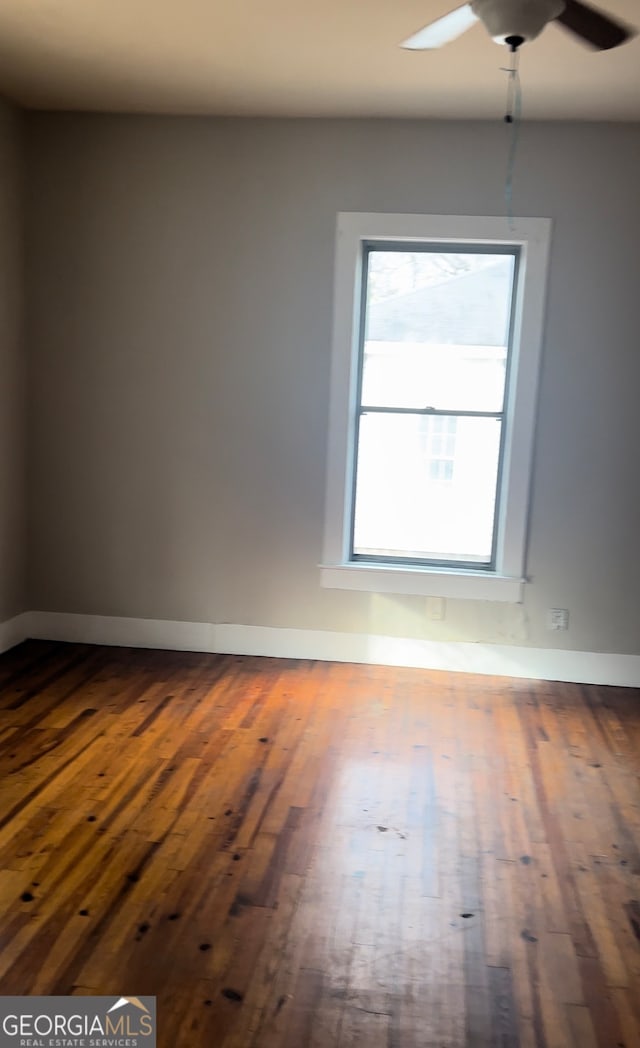 empty room featuring hardwood / wood-style flooring, a healthy amount of sunlight, and ceiling fan