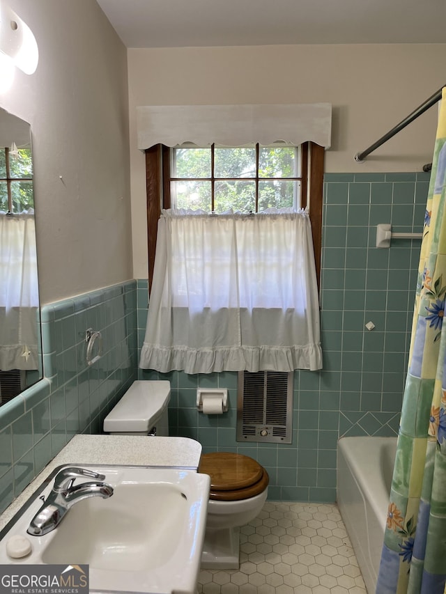 full bathroom with sink, tile walls, tile patterned floors, toilet, and shower / bath combo with shower curtain