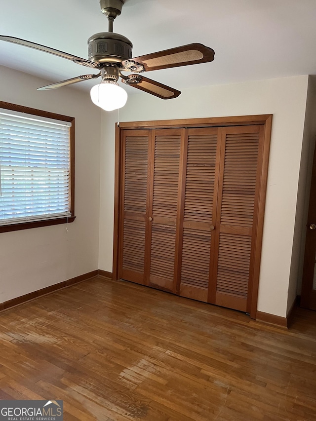 unfurnished bedroom with a closet, dark hardwood / wood-style floors, and ceiling fan