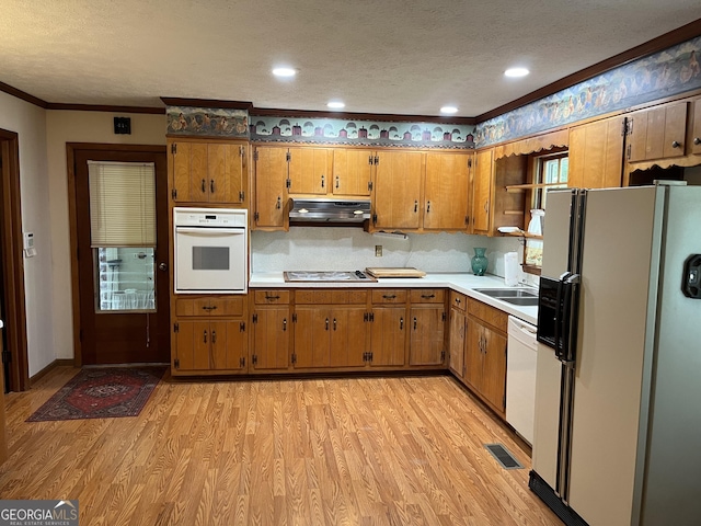 kitchen featuring white appliances, backsplash, ornamental molding, light hardwood / wood-style floors, and a textured ceiling