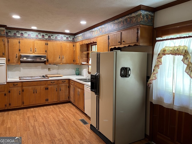 kitchen featuring crown molding, white appliances, backsplash, a textured ceiling, and light wood-type flooring