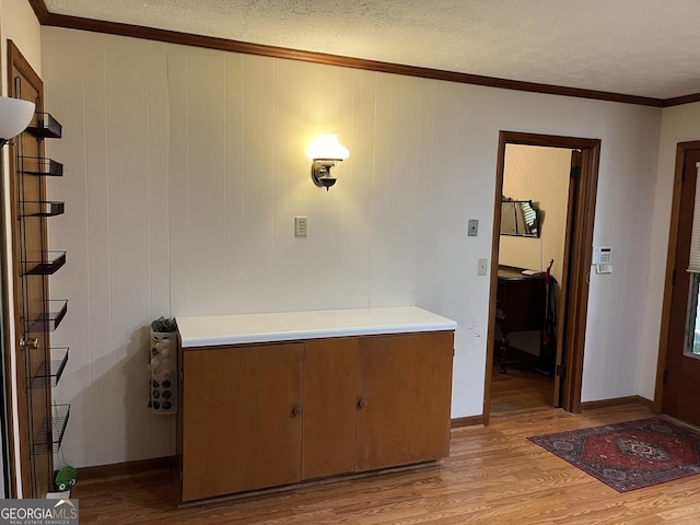 interior space featuring crown molding, a textured ceiling, and light hardwood / wood-style flooring