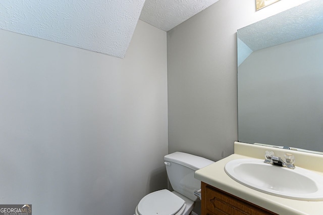 bathroom with vanity, toilet, and a textured ceiling