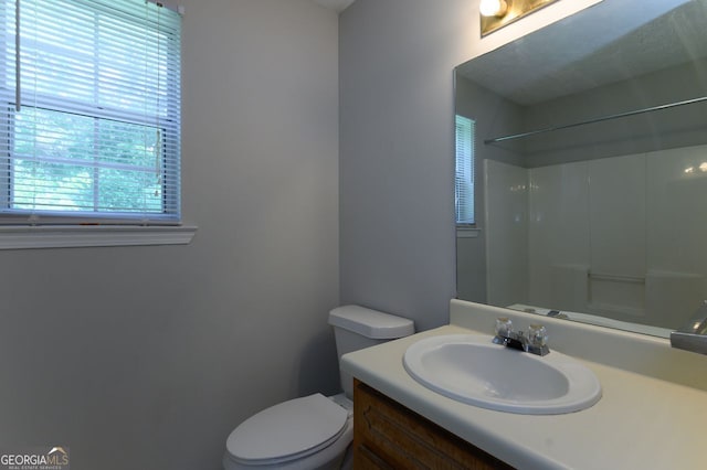 bathroom with vanity, toilet, a healthy amount of sunlight, and walk in shower